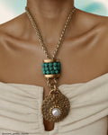 Necklace with turquoise beads and gold chain on a person wearing a white garment.